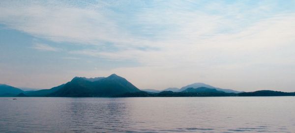 Scenic view of lake by mountains against sky