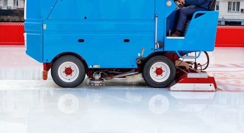 A stadium worker cleans the ice rink on a blue special modern ice cleaning machine. copy space.