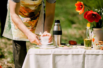 Midsection of man holding cup on table