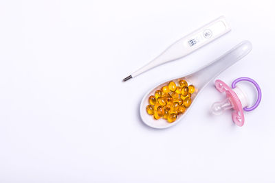 High angle view of medicines with thermometer and pacifier on white background