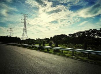 Wet road by trees against sky