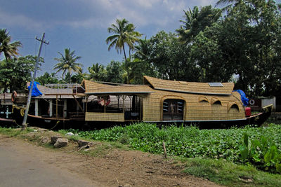 Built structure by trees on field against sky