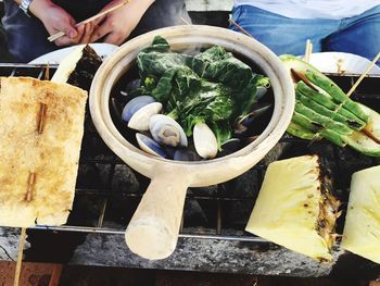 High angle view of people with food in claypot on barbeque