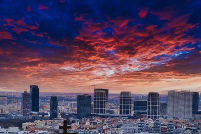 Buildings in city against dramatic sky