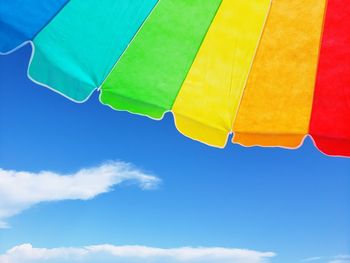 Low angle view of yellow umbrella against blue sky