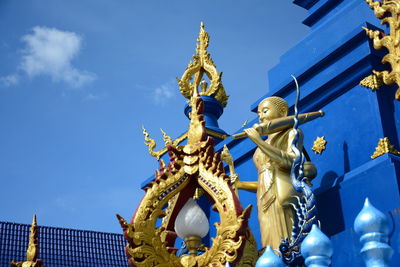 Low angle view of statue against blue sky and building