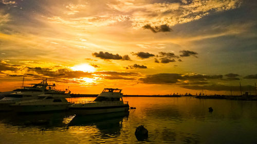 Silhouette of boats in sea during sunset