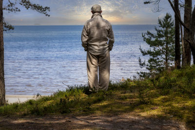 Rear view of man by sea against sky