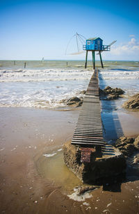 Blues fishing hut on beach against sky