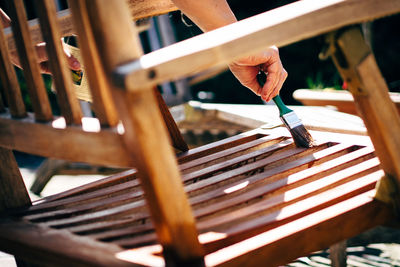 Midsection of man painting chair during sunny day