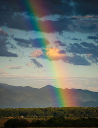 Scenic view of field against sky during sunset with rainbow