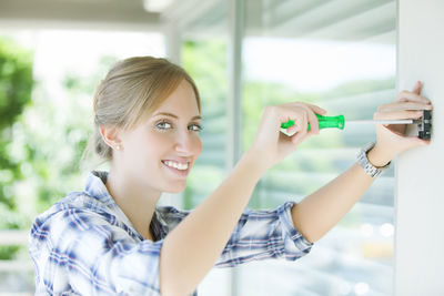Portrait of smiling woman fixing screw