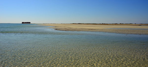 Scenic view of beach against clear blue sky