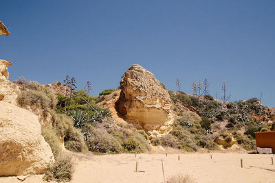 Rock formations on landscape against clear blue sky