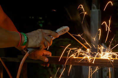 Blurred motion of man holding sparkler at night