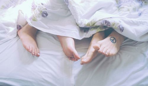 Low section of couple lying down on bed at home