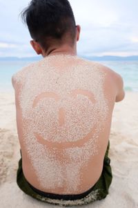 Rear view of shirtless man at beach against sky