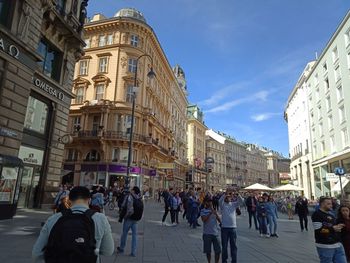 People walking on street amidst buildings in city