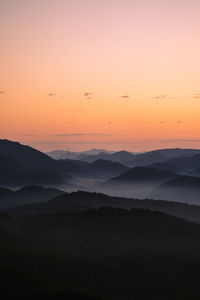 Scenic view of silhouette mountains against orange sky