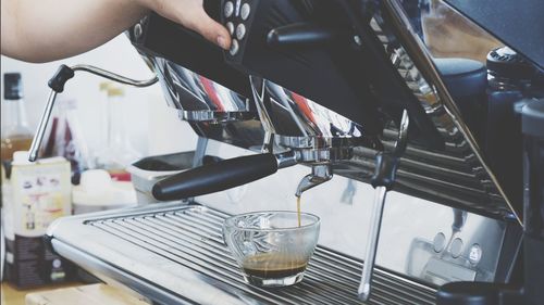 Cropped hand preparing coffee in cafe