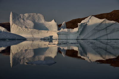 Scenic view of iceberg shapes and reflectins in mirror-like sea in greenland scoresby sound