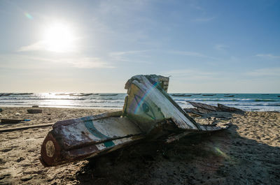 Abandoned boat on beach against sky