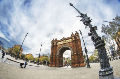 Low angle view of arc de triomf against cloudy sky