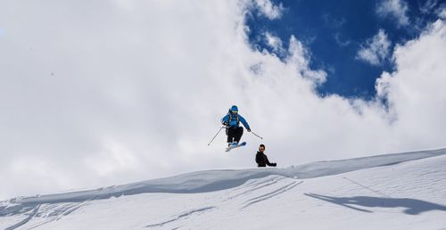 Person skiing on snowcapped mountain against cloudy sky