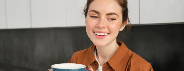 Portrait of young woman drinking coffee at home