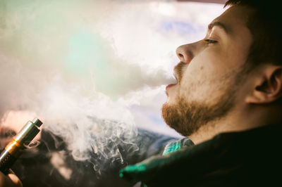 Side view of young man smoking cigarette