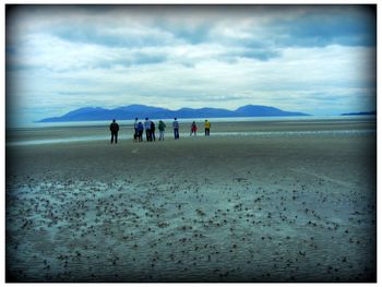 People walking on beach against sky