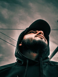 Low angle view of man looking at camera against sky