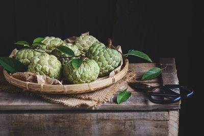 Close-up of vegetables in basket on table against black background