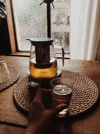 Midsection of person holding coffee cup on table at home