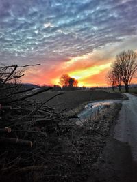 Snow covered field against sky during sunset