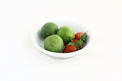 High angle view of fruits in plate against white background
