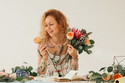 Young woman holding rose against white background