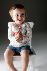 Portrait of a smiling girl sitting against black background