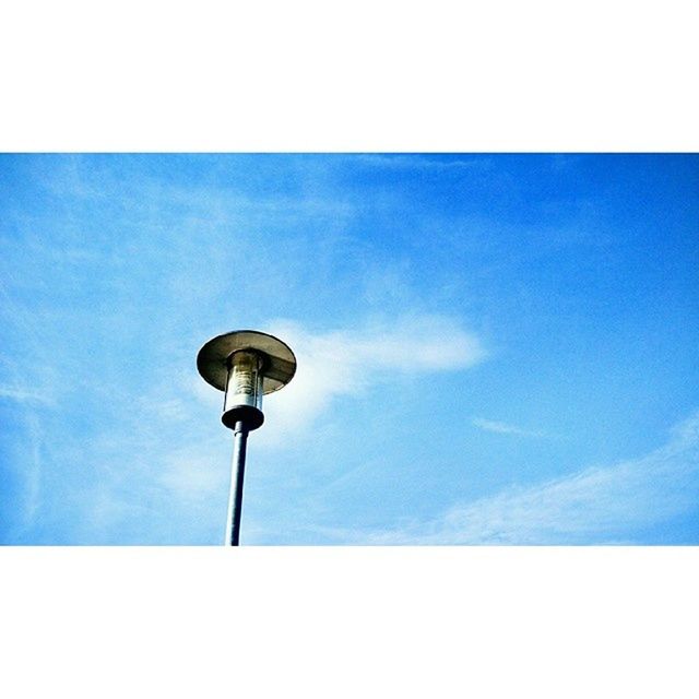 low angle view, street light, sky, blue, lighting equipment, built structure, building exterior, communications tower, tower, architecture, cloud, cloud - sky, lamp post, communication, pole, high section, tall - high, transfer print, outdoors, copy space