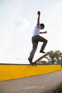 Low angle view of man jumping on pole against sky