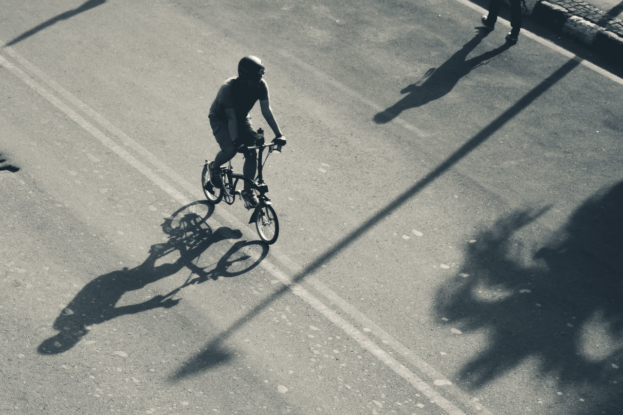 transportation, bicycle, shadow, men, sport, real people, sunlight, ride, riding, lifestyles, land vehicle, cycling, activity, city, full length, street, mode of transportation, motion, road, on the move, outdoors