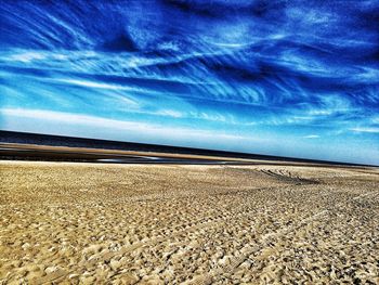 Surface level of sandy beach against blue sky