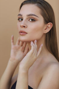 Portrait of beautiful young woman against beige background