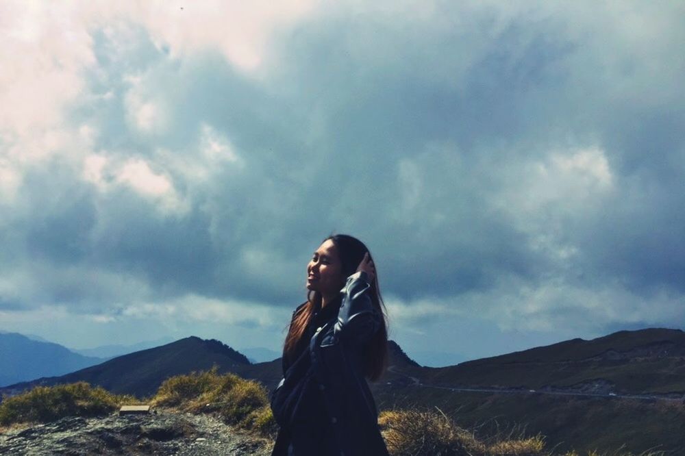 sky, cloud - sky, one person, mountain, real people, standing, beauty in nature, leisure activity, lifestyles, nature, scenics - nature, tranquility, three quarter length, day, non-urban scene, young adult, tranquil scene, young women, environment, mountain range, outdoors, hairstyle