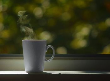 Close-up of coffee mug on window sill