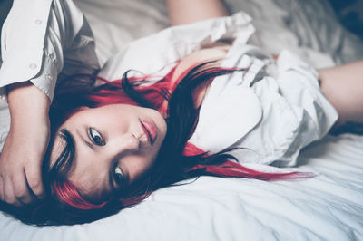 Close-up portrait of young woman relaxing on bed at home