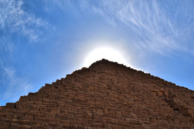 Low angle view of stone wall against cloudy sky