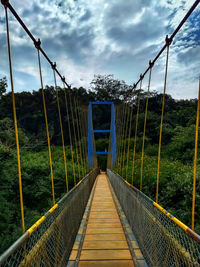 Footbridge against trees and sky