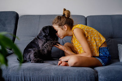 Side view of young woman using digital tablet while lying on sofa at home