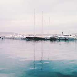 Sailboats moored in sea against sky